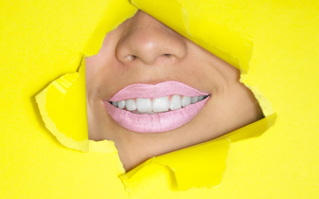Ripped, yellow wrapping paper exposes a pearly white smile underneath