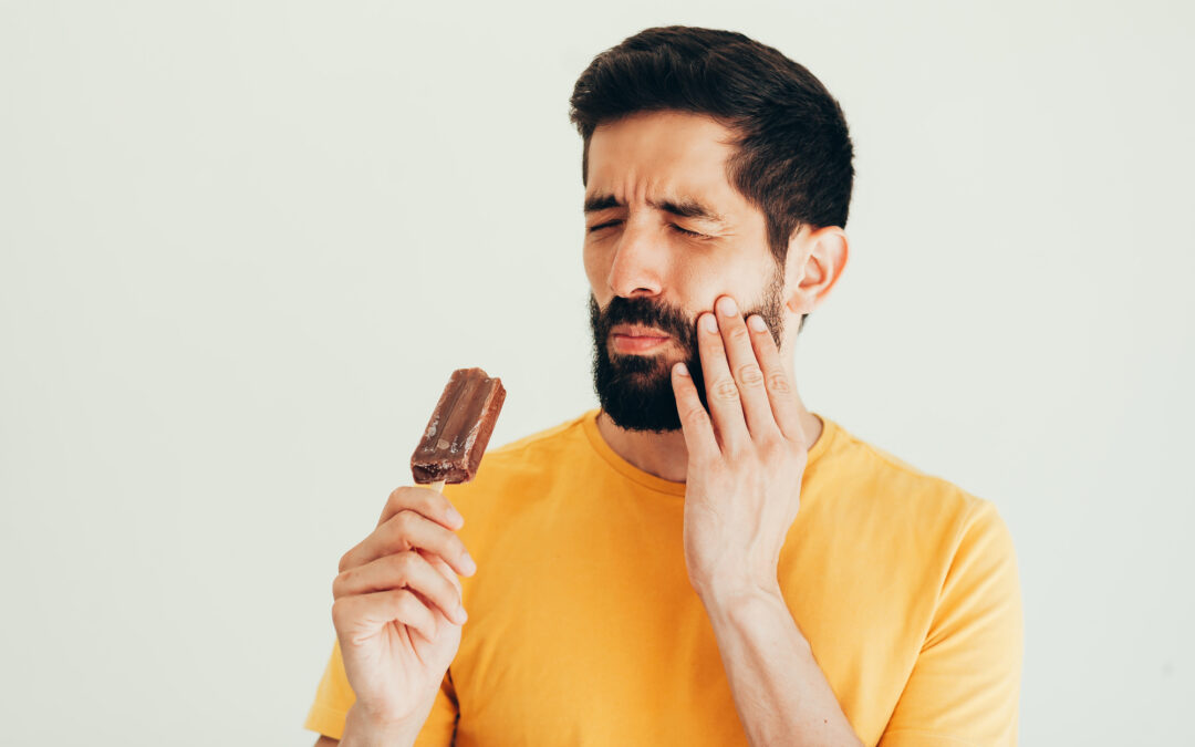 Man have sensitive teeth with ice on white background