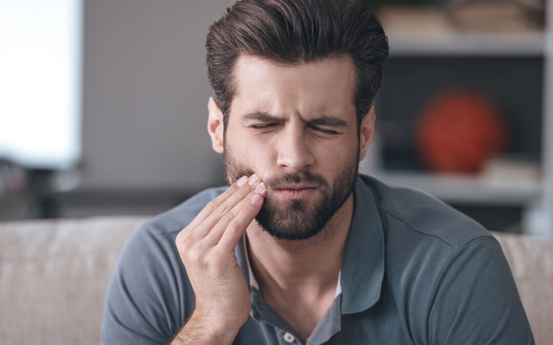 man wincing with tooth sensitivity