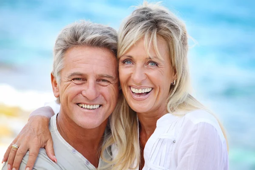 A happy couple smiles, showing off their healthy teeth