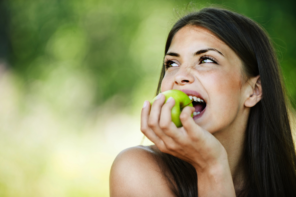 young woman eating a green apple