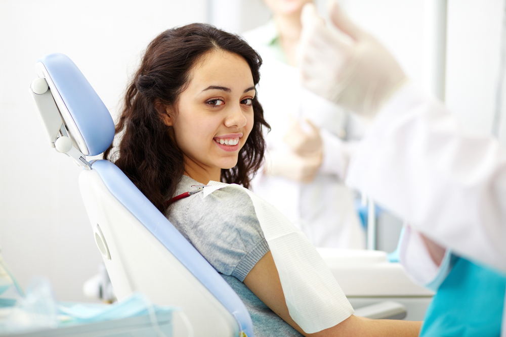woman with dark curly hair sitting in dental chair smiling waiting for IV sedation dentistry Naperville
