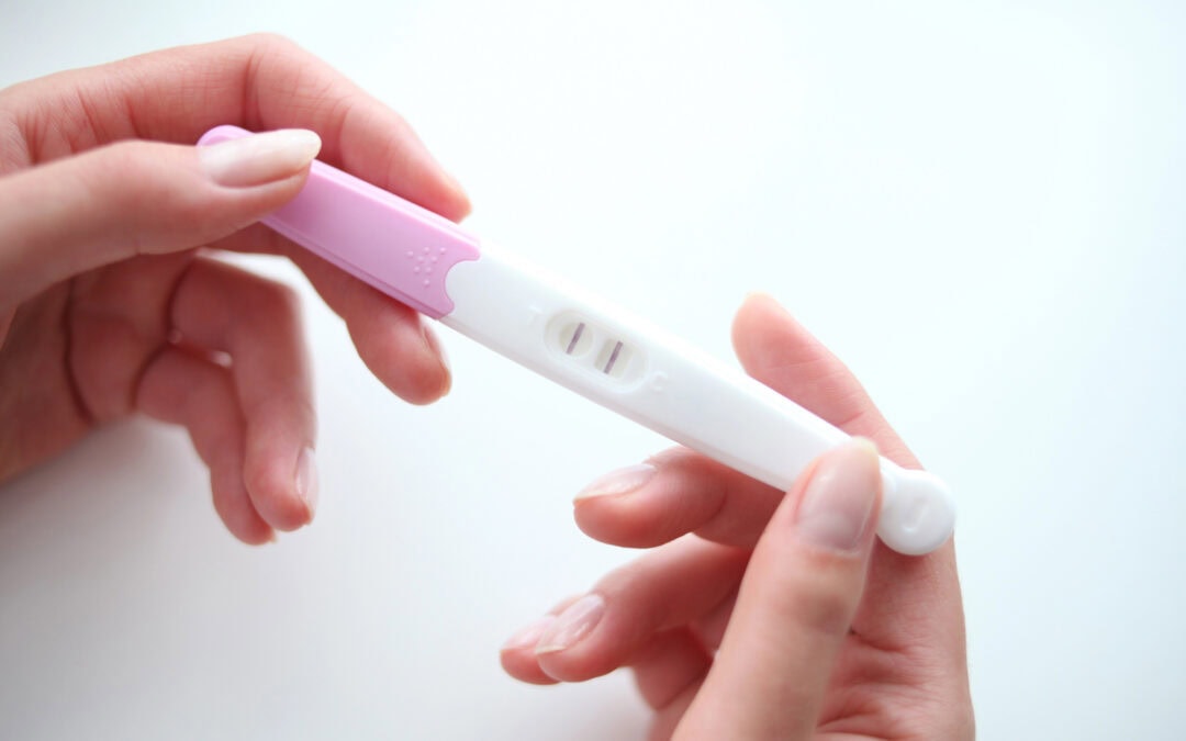 A woman's hands gently hold a pregnancy test after getting gum disease treatment from her Naperville dentist