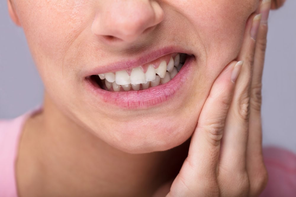 woman wincing from tooth pain