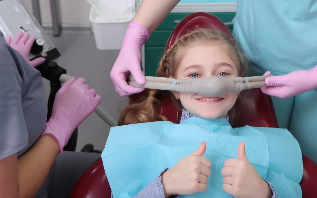 A little girl gives a thumbs up as she receives safe and effective sedation dentistry from her dentist in Naperville, IL.
