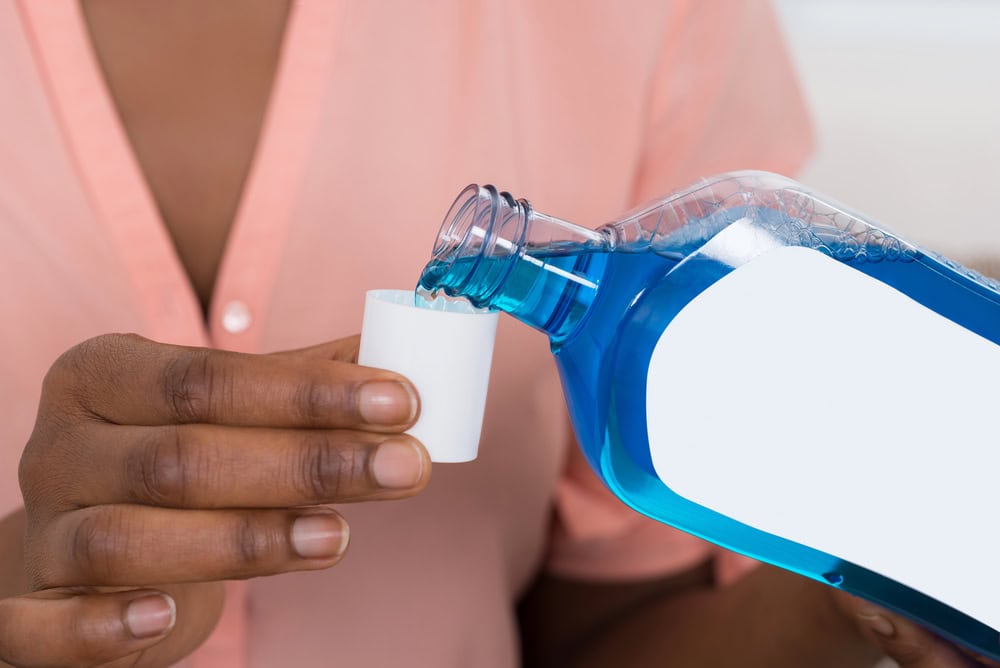 woman pouring mouthwash into small cup