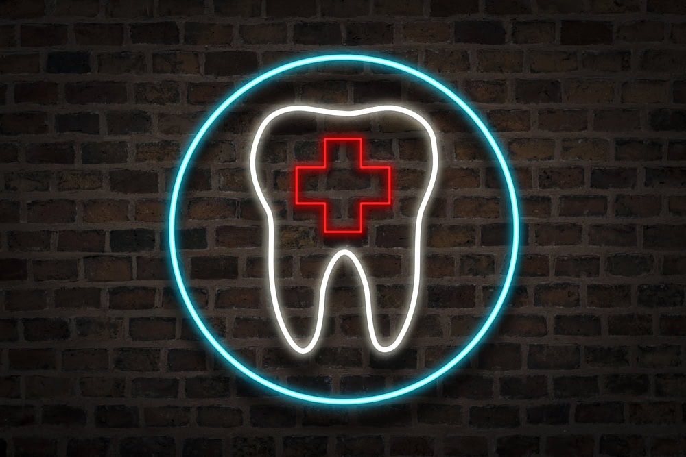 neon sign indicates emergency dentist with tooth and medical cross
